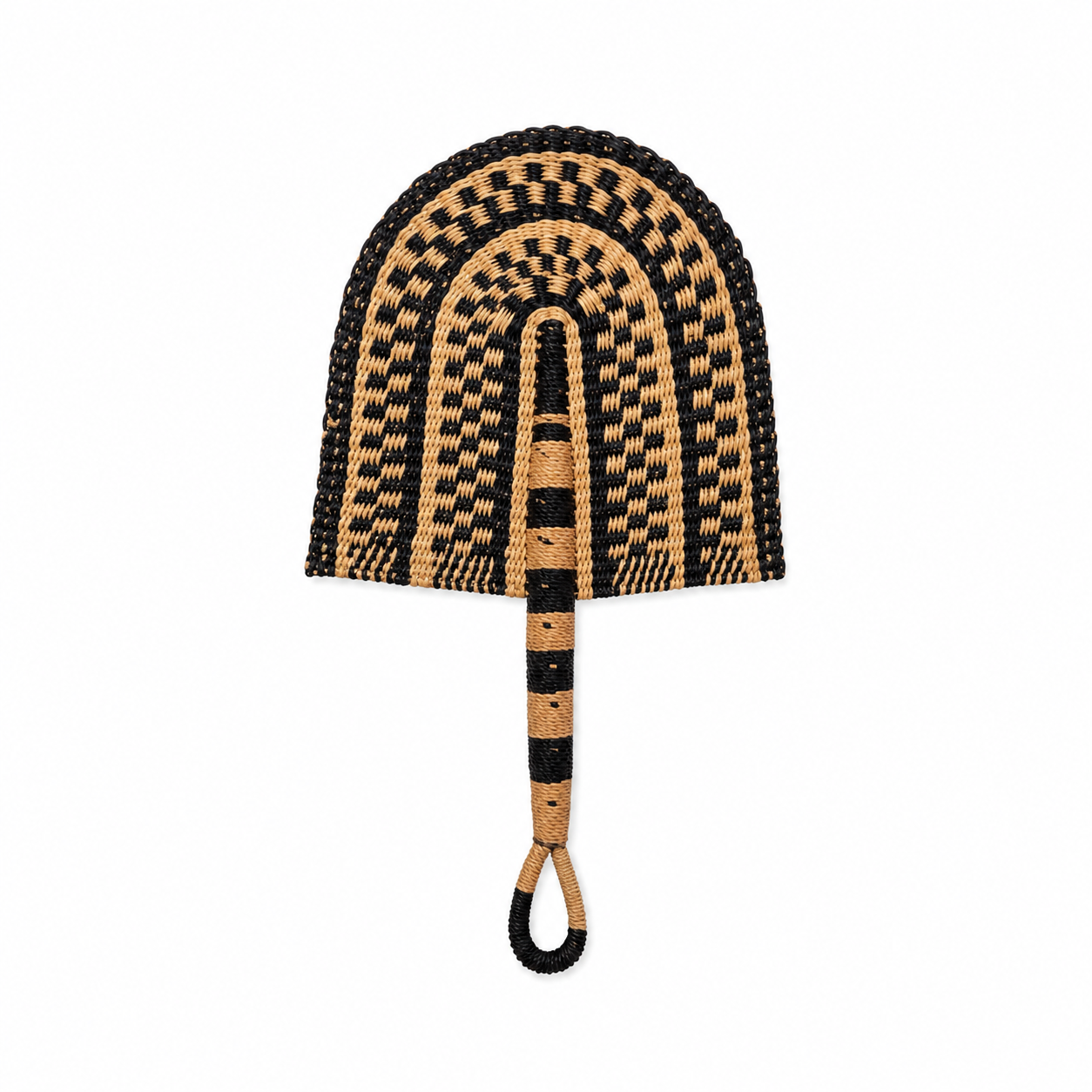 A hand-woven straw fan with a black and natural tan pattern, featuring a loop handle on a solid white background.