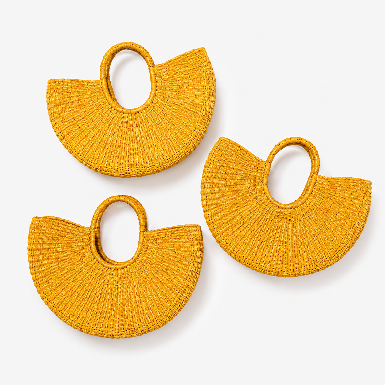 Three small woven handbags in a warm mustard yellow color, arranged on a light gray background. Each bag has a semicircular body with a loop handle at the top.
