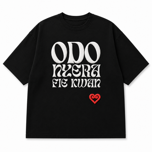 A black short-sleeve crewneck t-shirt featuring a stylized white text graphic on the front that reads 'ODO NYERA FIE KWAN' in a gothic font, with a small red heart logo underneath. The t-shirt is presented flat against a clean white background.