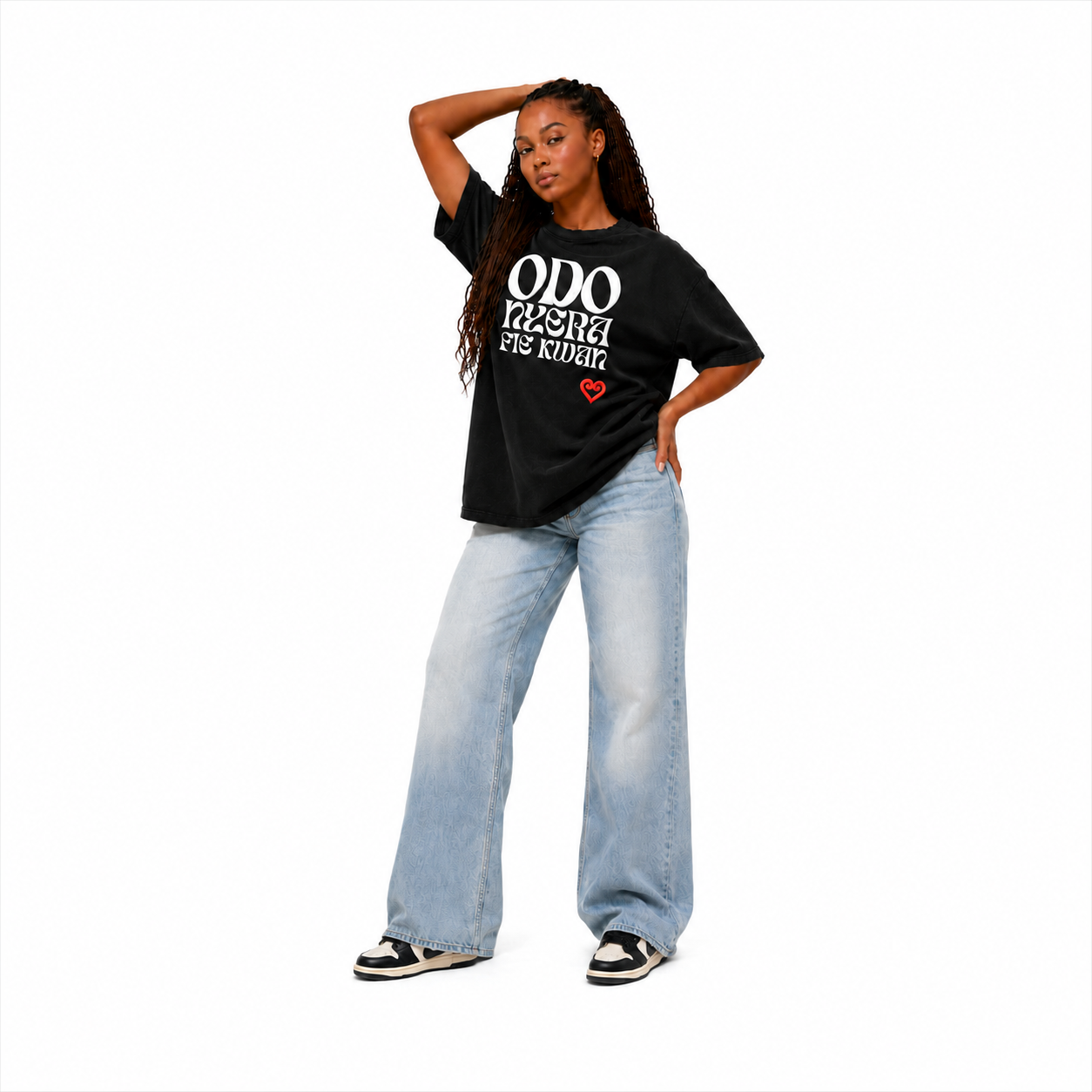 A woman modeling a black graphic t-shirt with white text that reads 'ODO MAMA I'M KIDDIN'' and a small red heart, paired with light-wash wide-leg jeans and black-and-white sneakers, against a plain white background.