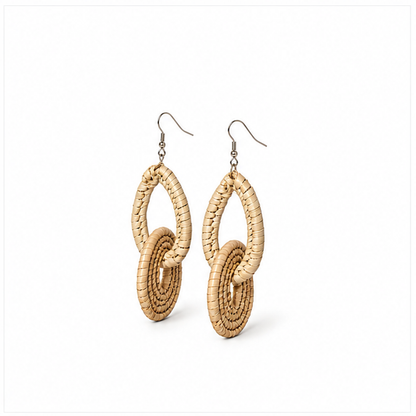 A pair of bohemian-style dangle earrings made of woven natural straw or raffia, featuring interlocking oval and spiral loops hanging from silver fishhook wires, shown on a plain white background.