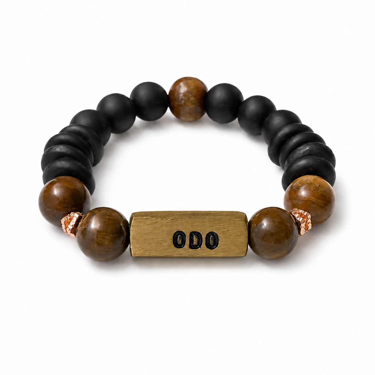 A beaded stretch bracelet featuring matte black round beads, polished brown tiger's eye beads, and a central rectangular brass spacer engraved with 'ODO'.