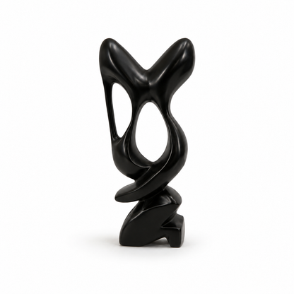 A modern abstract black sculpture with a glossy finish, featuring organic flowing shapes and hollow cutouts, standing on a small sculptural base against a plain white background.