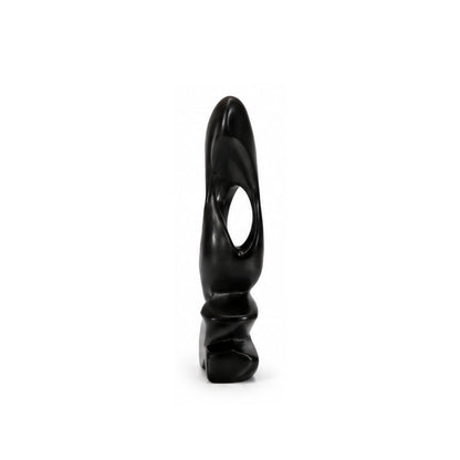 A small black sculptural object with a smooth glossy finish, featuring a curved organic shape and a central oval cutout, standing upright on a white background.