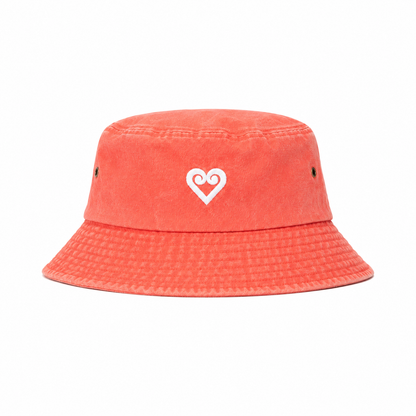 A coral orange bucket hat made of textured canvas, featuring a white embroidered heart logo on the front and small ventilation eyelets on the sides, set against a plain white background.