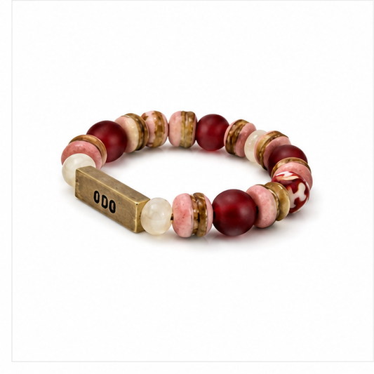 A beaded stretch bracelet featuring round and oval beads in deep red, dusty pink, cream, and metallic gold, with a rectangular gold clasp engraved with '0D0'.