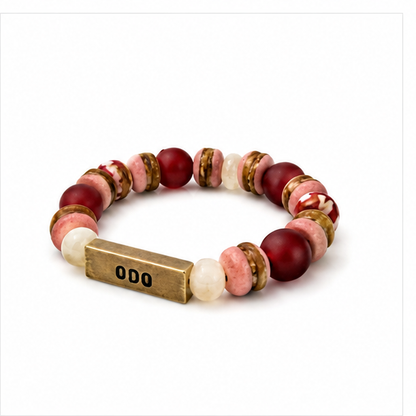 A beaded stretch bracelet featuring dark red, pink, and white marbled beads, gold-toned spacer rings, and a rectangular gold-toned metal clasp engraved with 'ODO'.