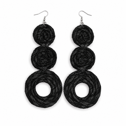 A pair of black rafiia braided dangle earrings with three stacked spiral rings on each earring, suspended from silver fishhook wires, shown against a plain white background.