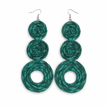 A pair of handmade dangle earrings made from three stacked spiral layers of woven teal green raffia paper, suspended from silver fishhook wires, shown against a plain white background.