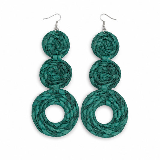 A pair of handmade dangle earrings made from three stacked spiral layers of woven teal green raffia paper, suspended from silver fishhook wires, shown against a plain white background.