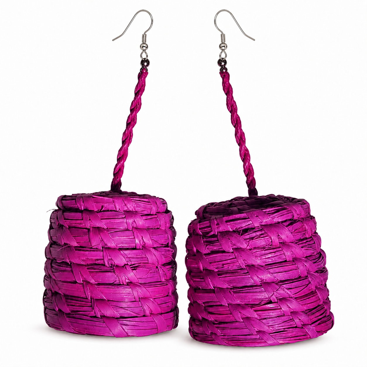 A pair of magenta woven raffia dangle earrings with silver fishhook ear wires, shown against a plain white background.