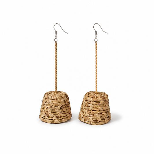 A pair of dangling earrings made from natural woven straw or seagrass in a tapered cone shape, hanging from twisted rope stems and silver fishhook ear wires, shown against a plain white background.
